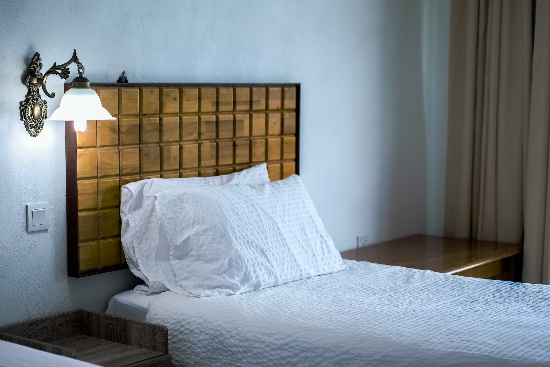 white bedding cover beside brown wooden side table